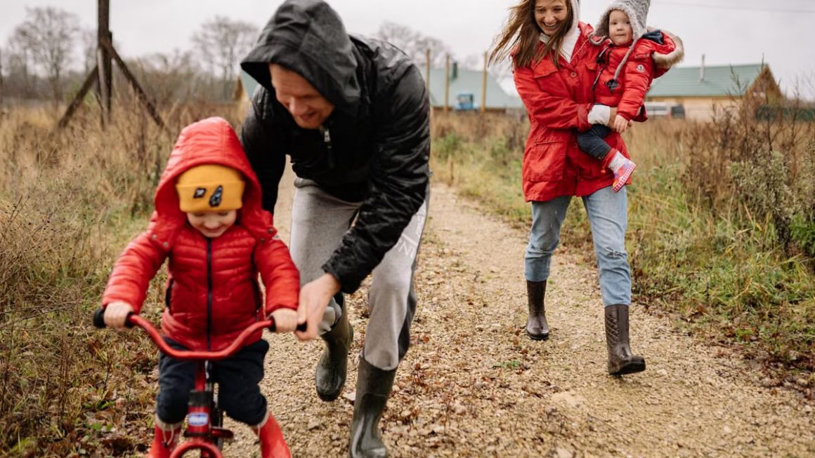 Family enjoying a joyful autumn walk along a rustic dirt road in vibrant outfits.